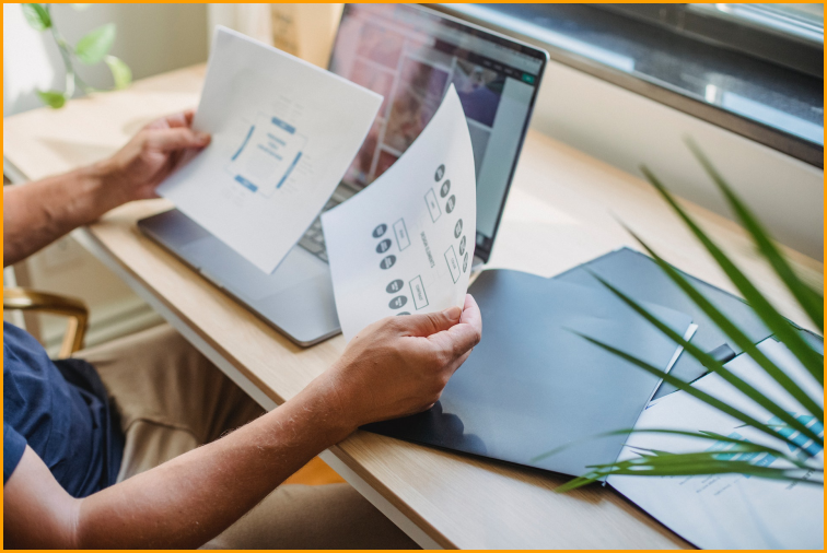 Person holding pieces of paper working on the wireframe planning for their client's new website design.